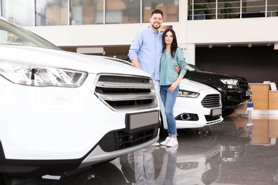 Photo of Young couple buying new car in salon