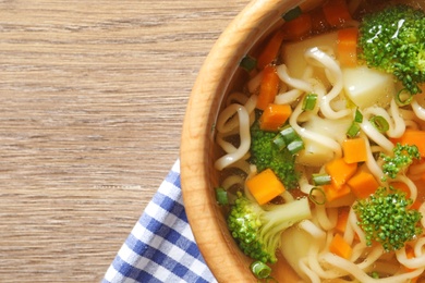 Bowl of fresh homemade vegetable soup on wooden background, top view. Space for text