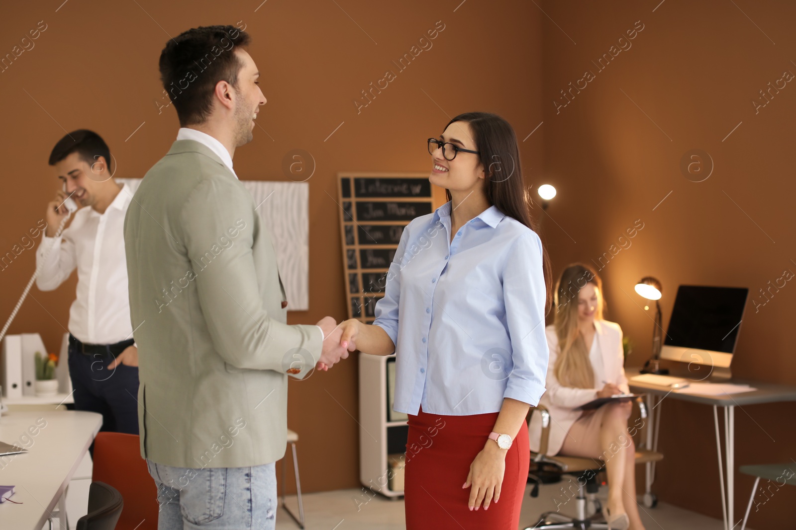 Photo of Human resources manager shaking hands with applicant during job interview in office