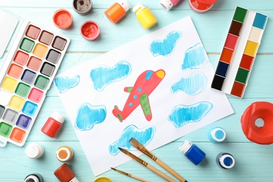 Photo of Flat lay composition with child's painting of airplane on table