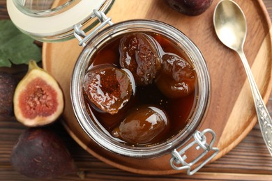 Photo of Jar of tasty sweet jam and fresh figs on wooden table, flat lay