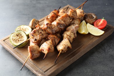 Photo of Delicious shish kebabs with vegetables and lemon on grey table