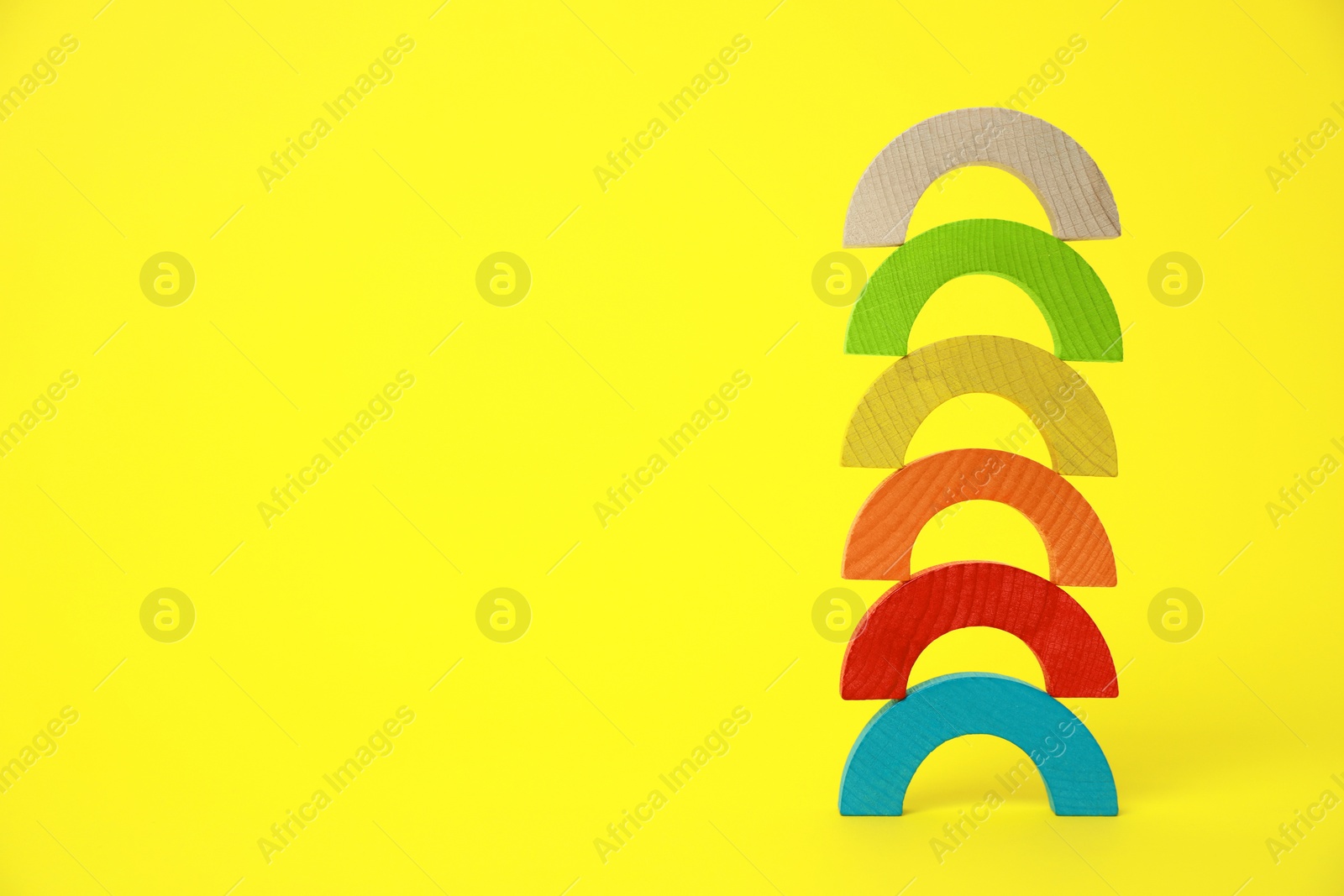 Photo of Colorful wooden pieces of playing set on yellow background, space for text. Educational toy for motor skills development