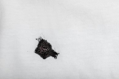 Stain of black ink on white shirt, top view. Space for text