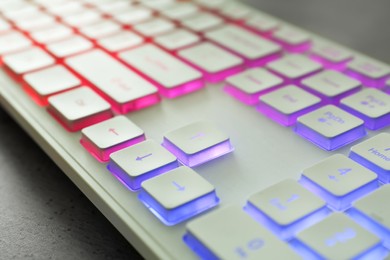 Photo of Modern keyboard with RGB lighting on grey table, closeup