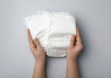 Photo of Woman with diapers on light grey background, closeup