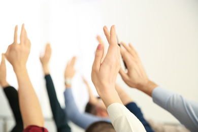 Photo of People raising hands to ask questions at business training on light background, closeup