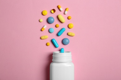 Flat lay composition with bottle and pills on color background