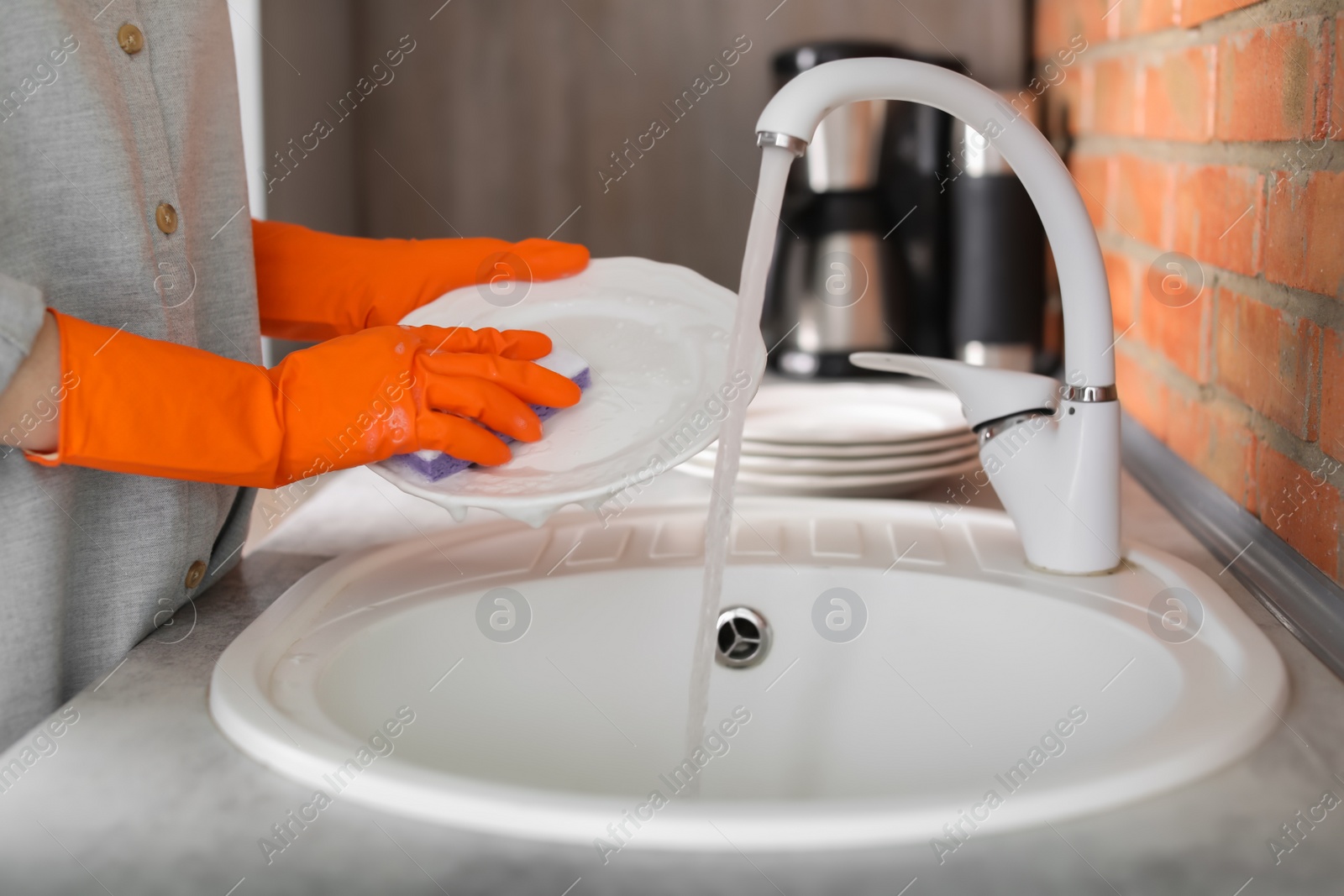 Photo of Young woman washing dishes in kitchen