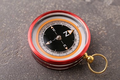 One compass on grey textured background, closeup. Navigation equipment