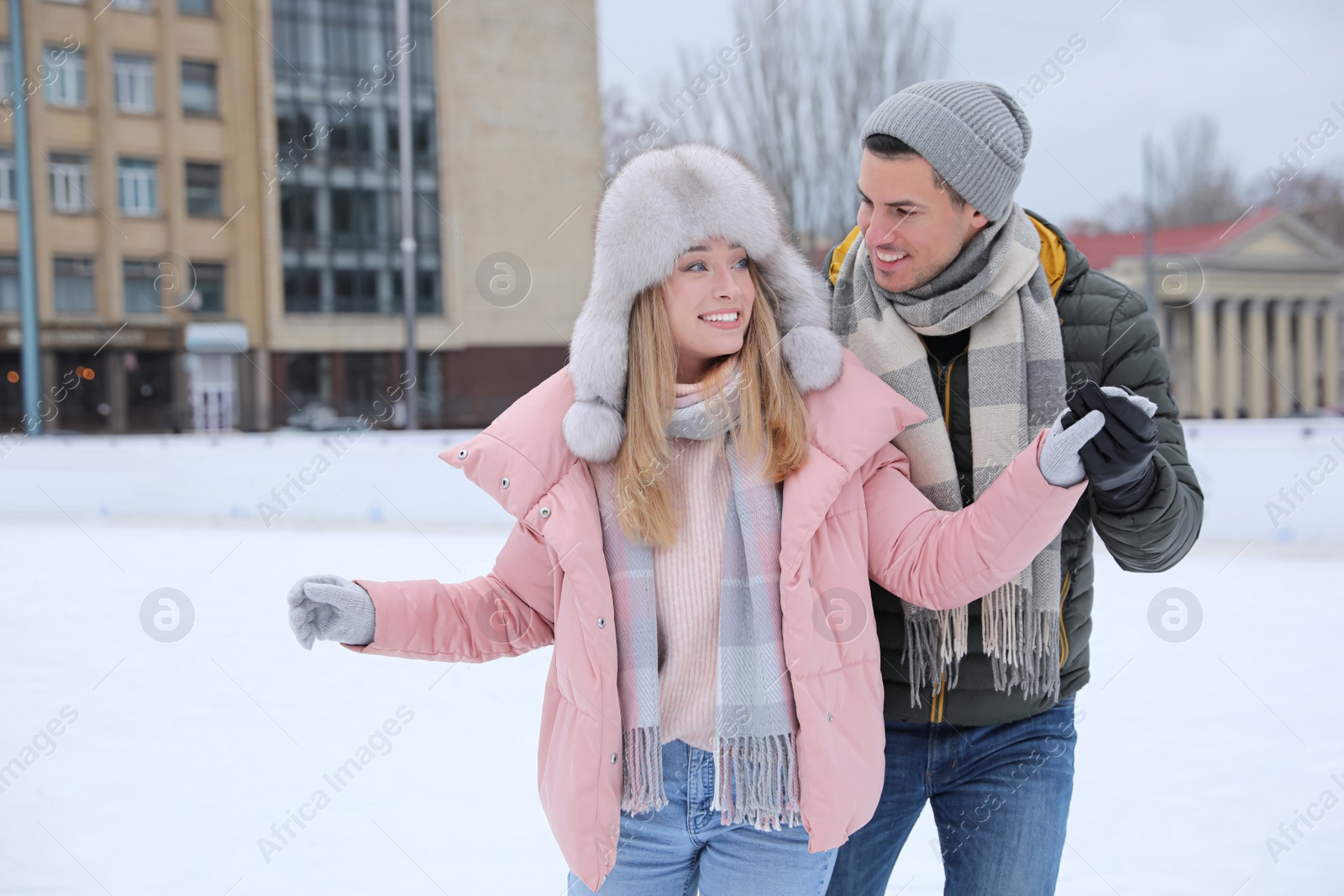 Image of Happy couple skating along ice rink outdoors