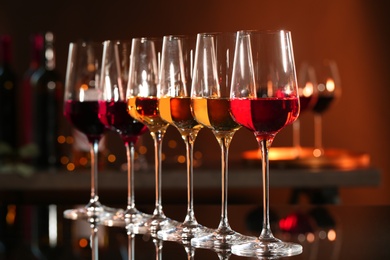 Photo of Row of glasses with different wines on bar counter against blurred background