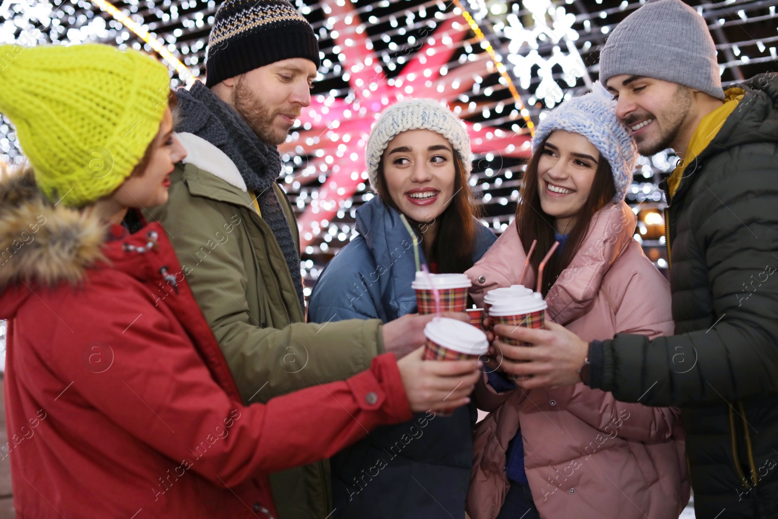 Photo of Happy friends with cups of mulled wine at winter fair