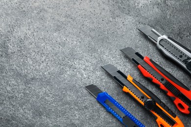 Photo of Different utility knives on grey table, flat lay. Space for text