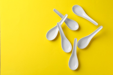 Miso soup spoons on yellow background, flat lay. Space for text