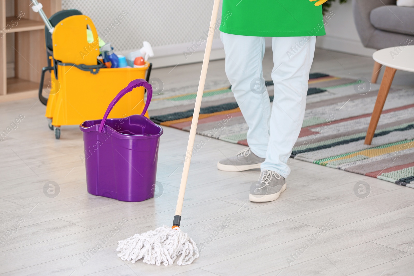 Photo of Man cleaning floor with mop in living room