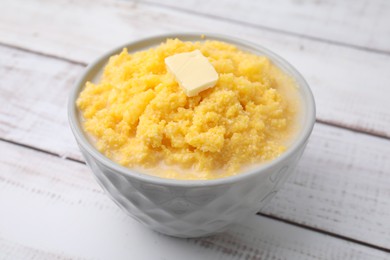 Photo of Tasty cornmeal with butter in bowl on white wooden table, closeup