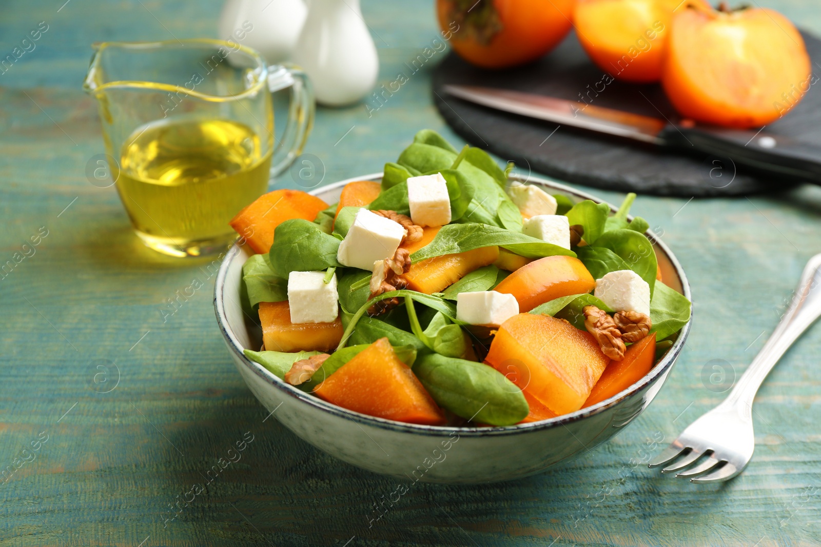 Photo of Delicious persimmon salad served on light blue wooden table