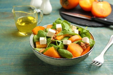 Delicious persimmon salad served on light blue wooden table