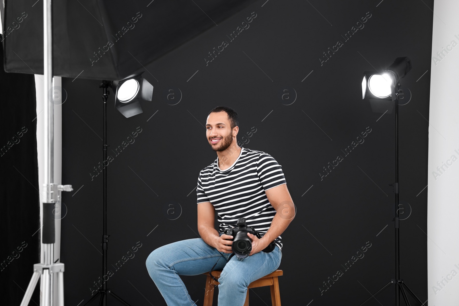 Photo of Young professional photographer with camera in modern photo studio