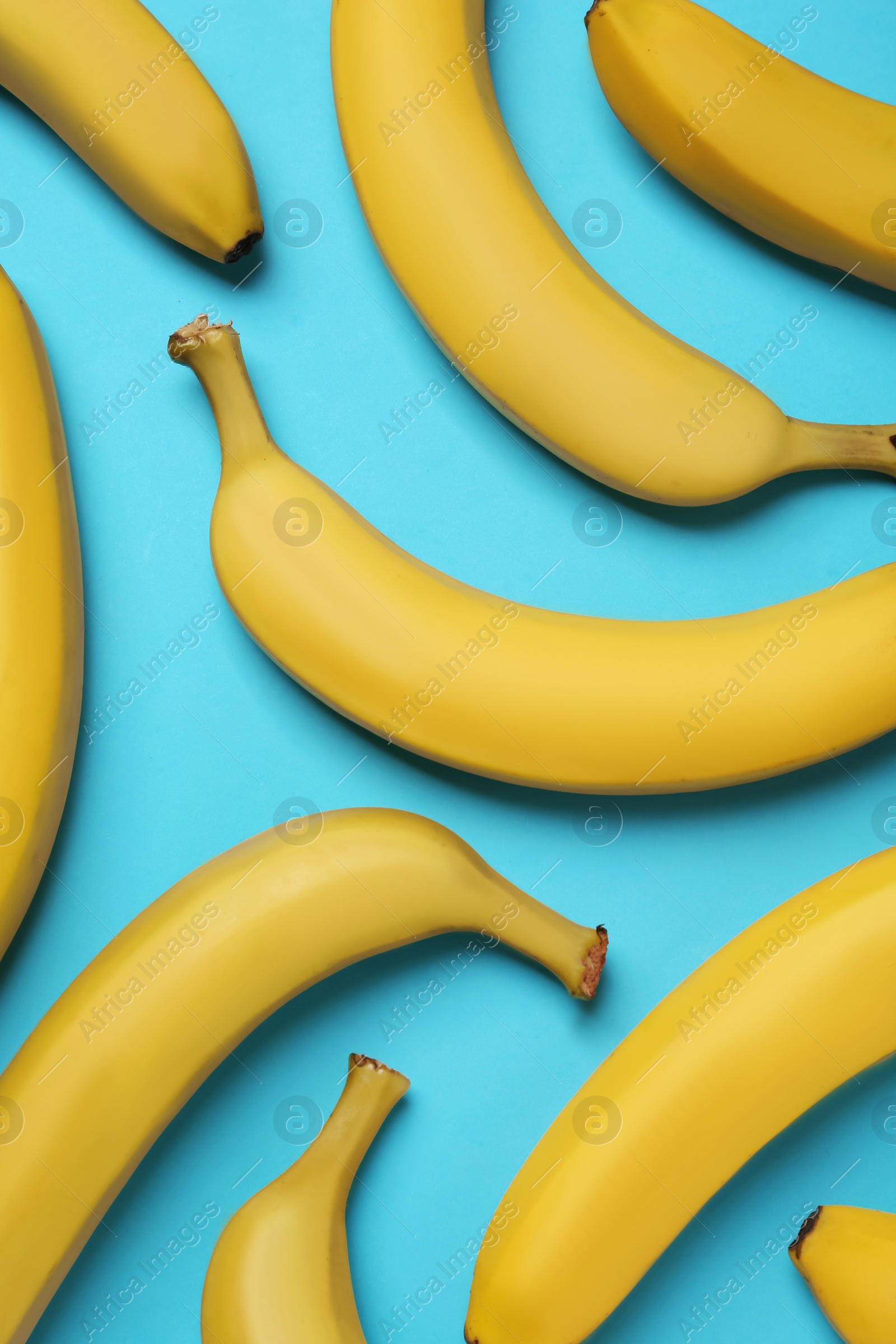 Photo of Ripe yellow bananas on turquoise background, flat lay