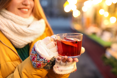 Woman with mulled wine at winter fair, closeup