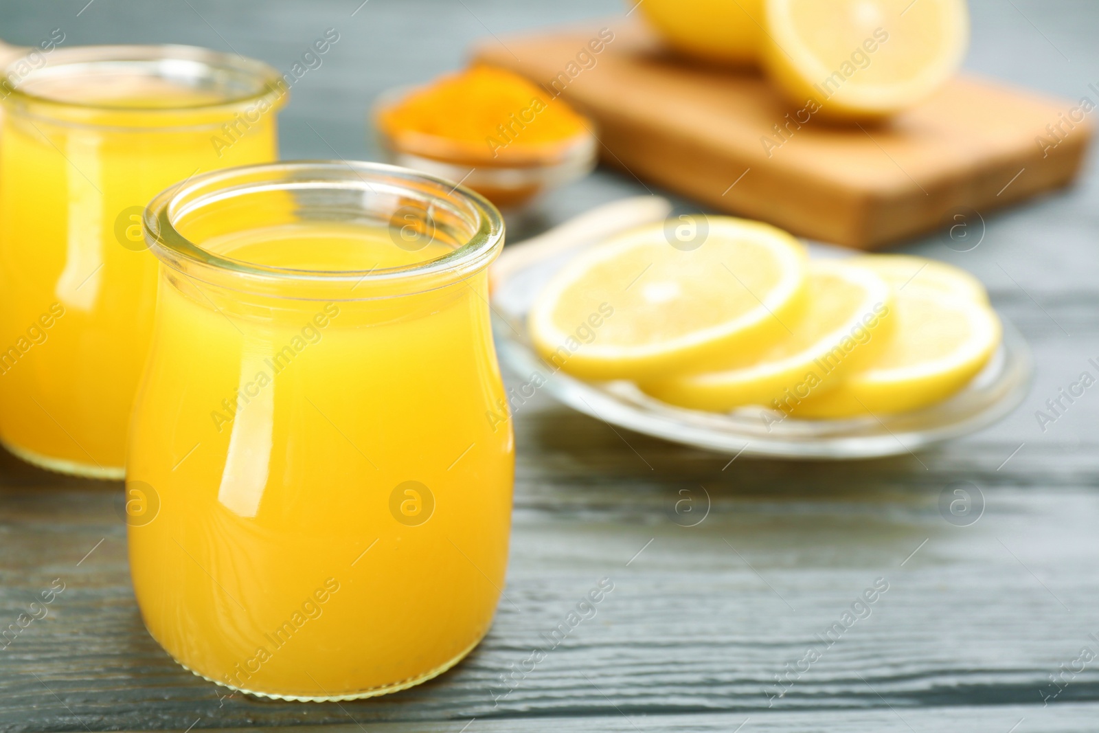 Photo of Immunity boosting drink and ingredients on grey wooden table, closeup. Space for text