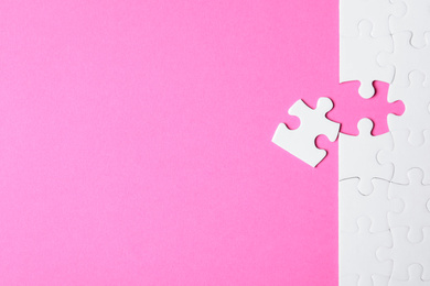 Photo of Blank white puzzle with separated piece on pink background, flat lay. Space for text