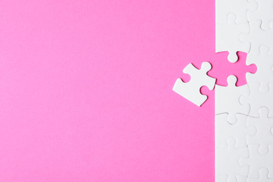 Blank white puzzle with separated piece on pink background, flat lay. Space for text