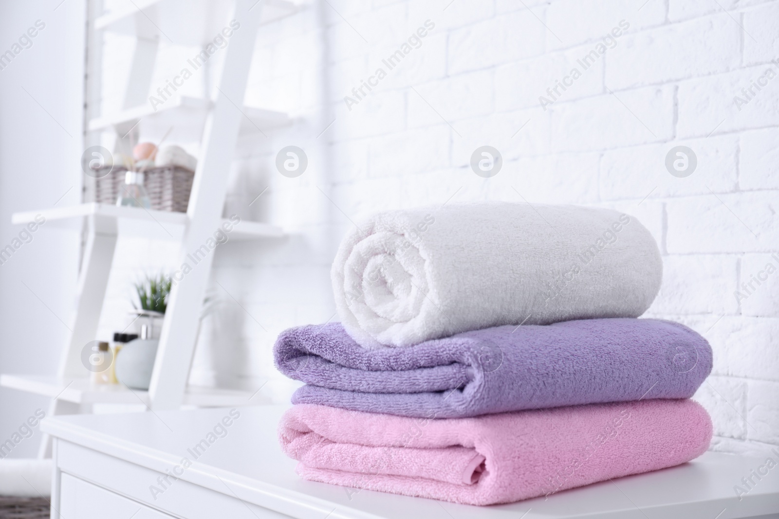 Photo of Stack of fresh towels on table in bathroom. Space for text