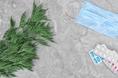 Photo of Ragweed (Ambrosia) with face mask and allergy medication on grey marble background, flat lay. Space for text