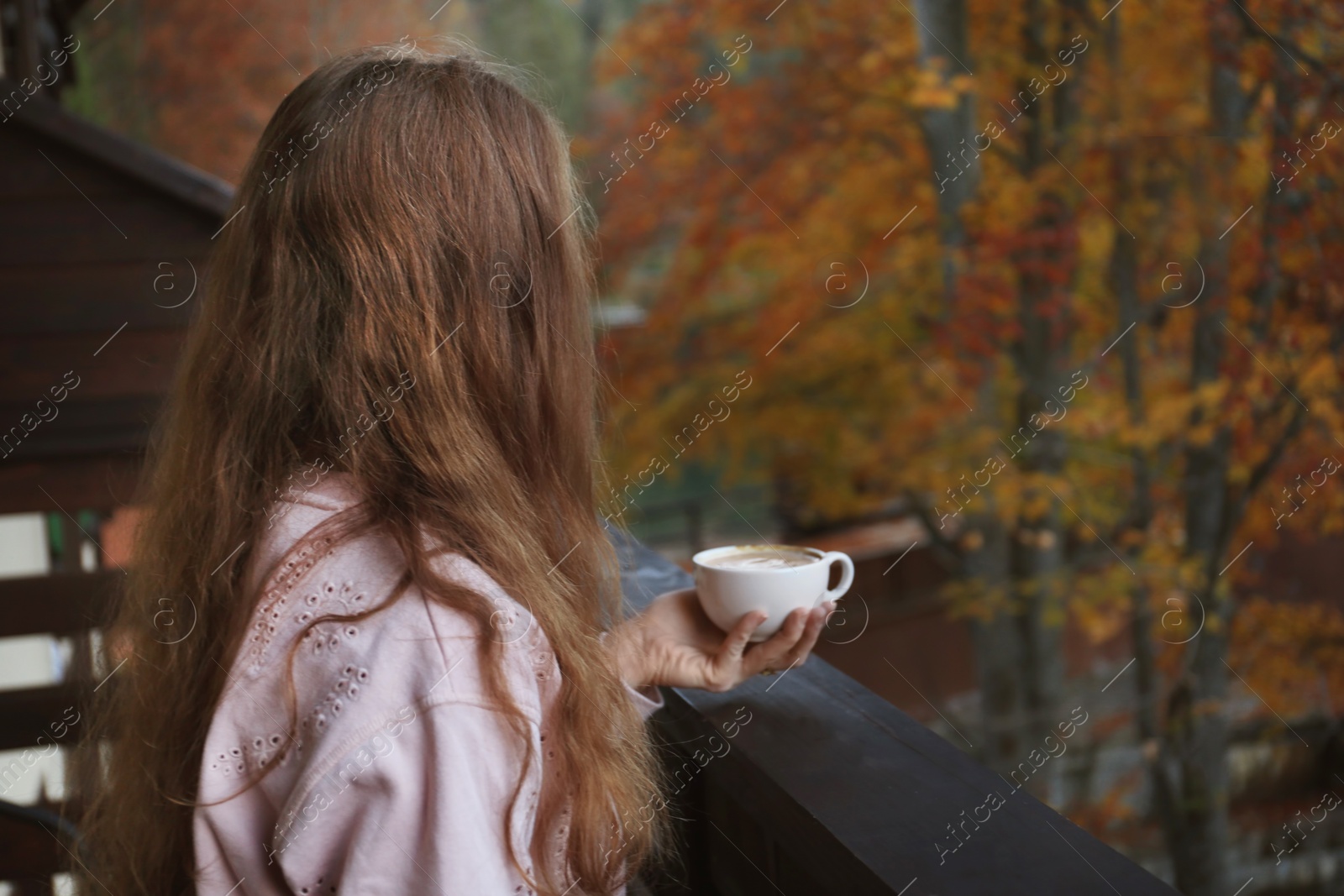 Photo of Woman enjoying cup of hot cozy drink on balcony