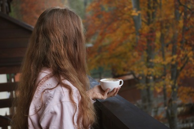 Photo of Woman enjoying cup of hot cozy drink on balcony