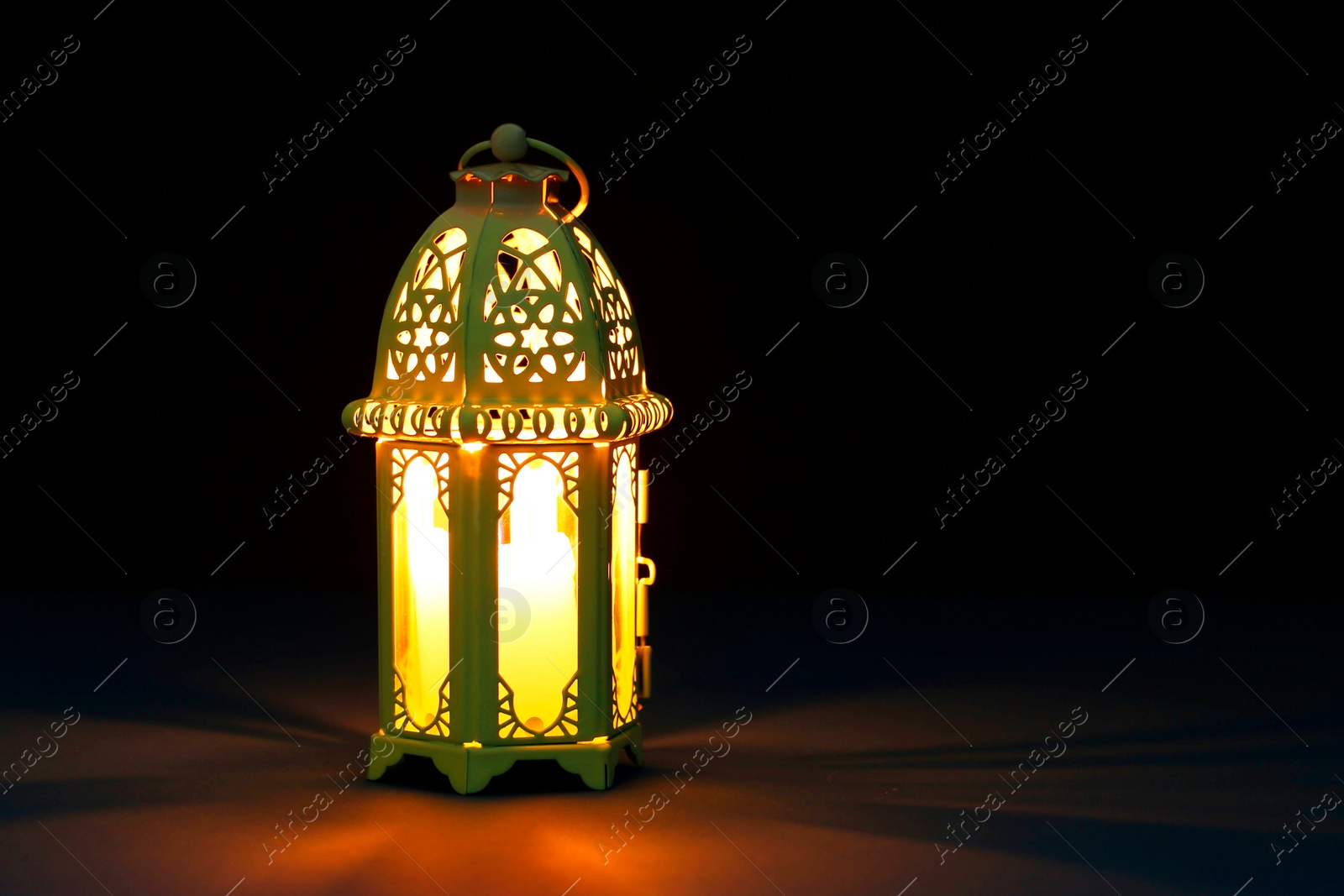 Photo of Decorative Arabic lantern on table against dark background. Space for text