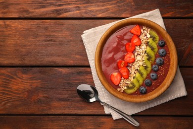 Photo of Bowl of delicious smoothie with fresh blueberries, strawberries, kiwi slices and oatmeal on wooden table, flat lay. Space for text