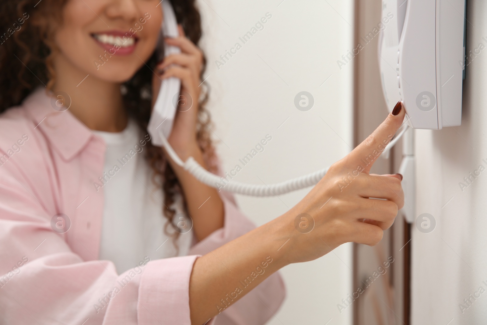 Photo of African-American woman pressing button on intercom panel indoors, closeup