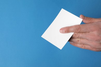 Photo of Man holding paper card on blue background, closeup. Mockup for design