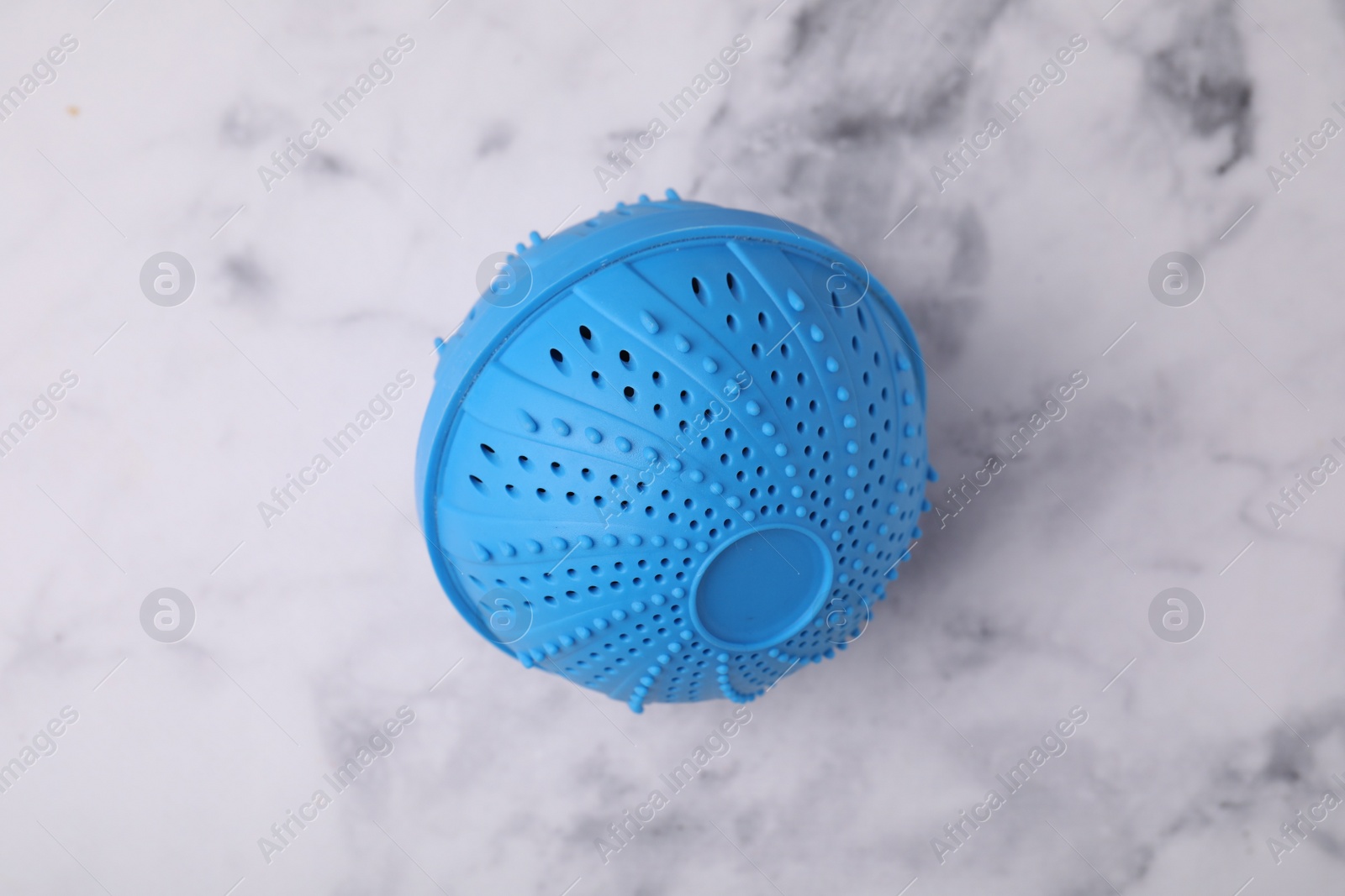 Photo of Dryer ball for washing machine on white marble table, top view