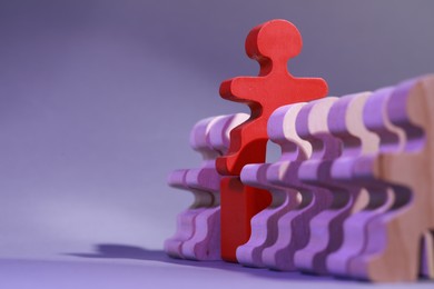 Photo of Wooden figures with red one on purple background, closeup and space for text. Recruiter searching employee