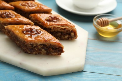 Photo of Delicious sweet baklava with walnuts on turquoise wooden table, closeup