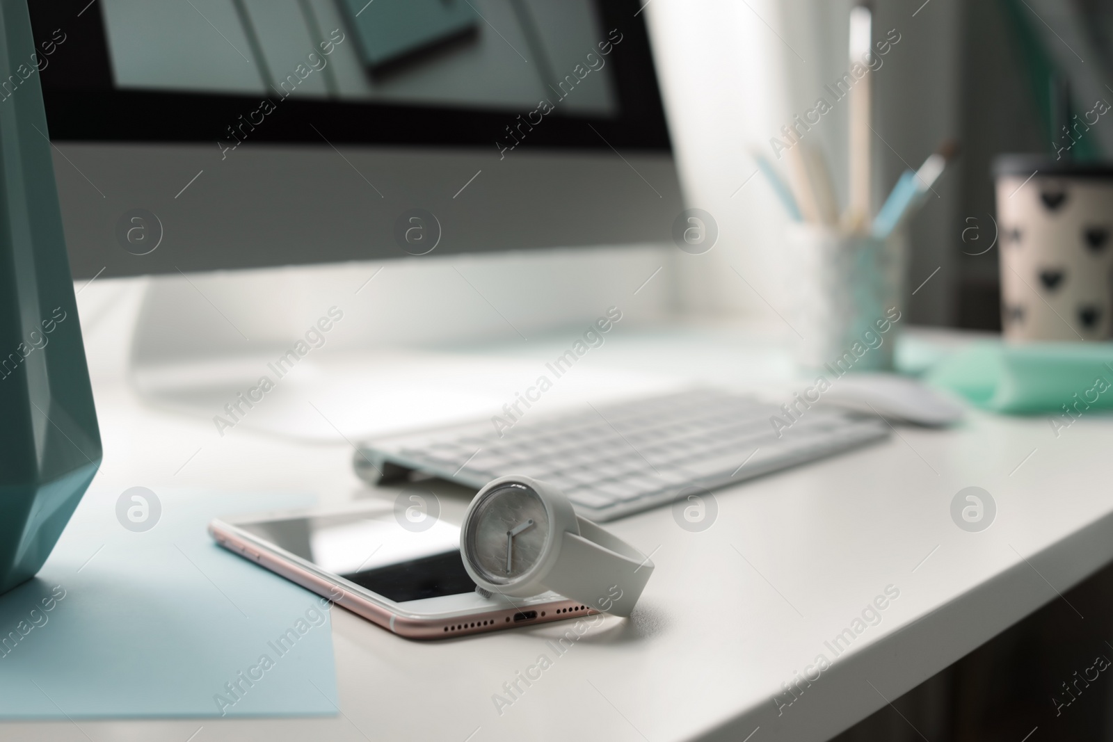 Photo of Stylish workplace with modern computer on desk, space for text. Focus on watch and smartphone