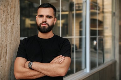 Portrait of handsome bearded man near building outdoors. Space for text