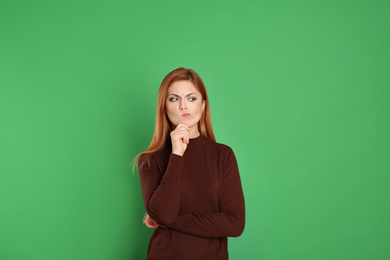 Photo of Pensive woman on green background. Thinking about answer for question