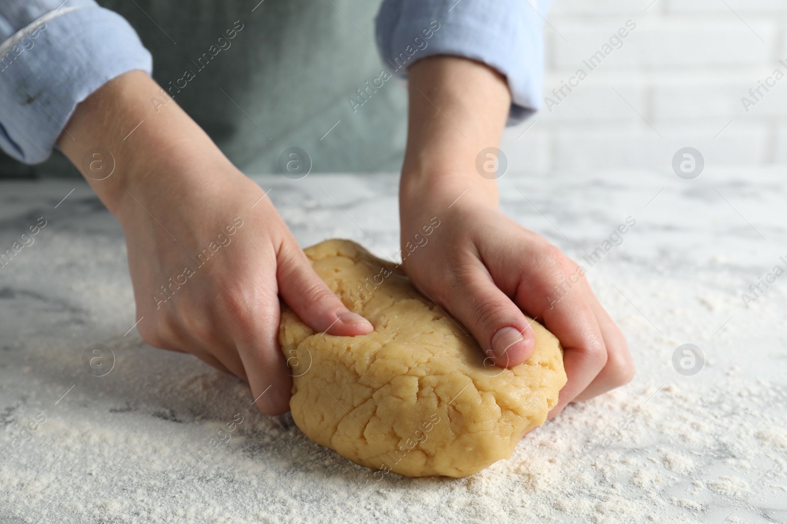 Photo of Making shortcrust pastry. Woman kneading raw dough at white marble table, closeup