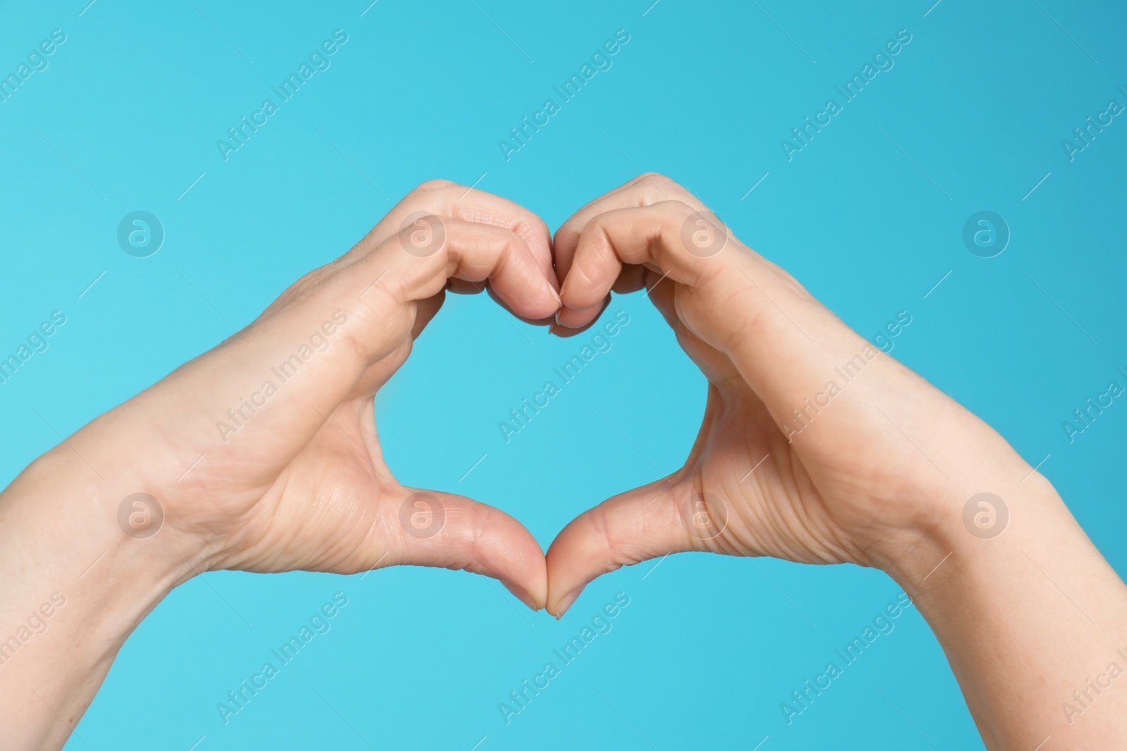 Photo of Woman making heart with her hands on color background, closeup