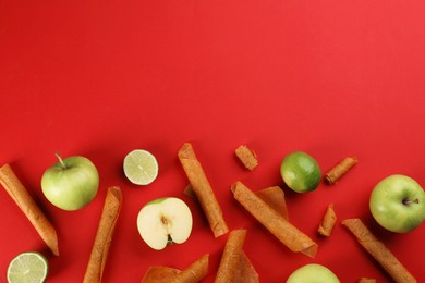 Photo of Delicious fruit leather rolls, apples and limes on red background, flat lay. Space for text