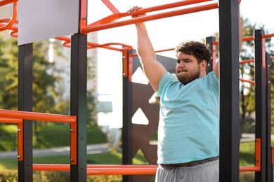Young overweight man training on sports ground