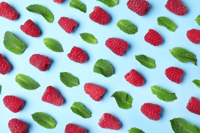 Flat lay composition with delicious ripe raspberries and leaves on blue background