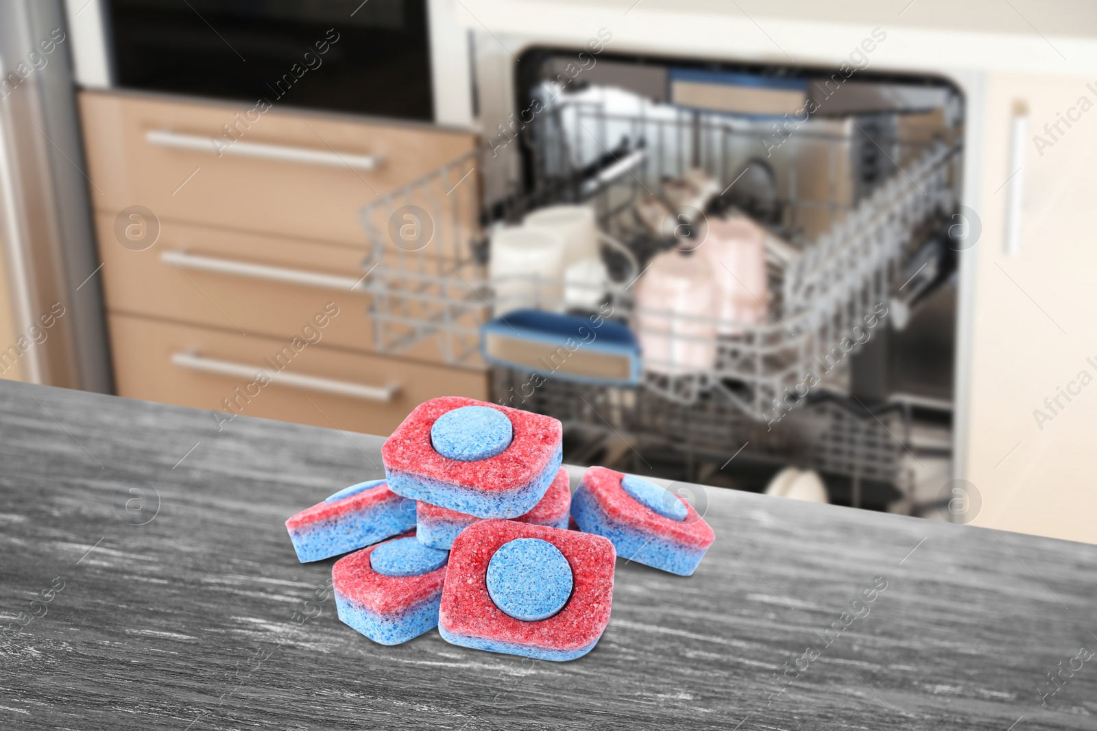 Image of Dishwasher detergent tablets on wooden table in kitchen