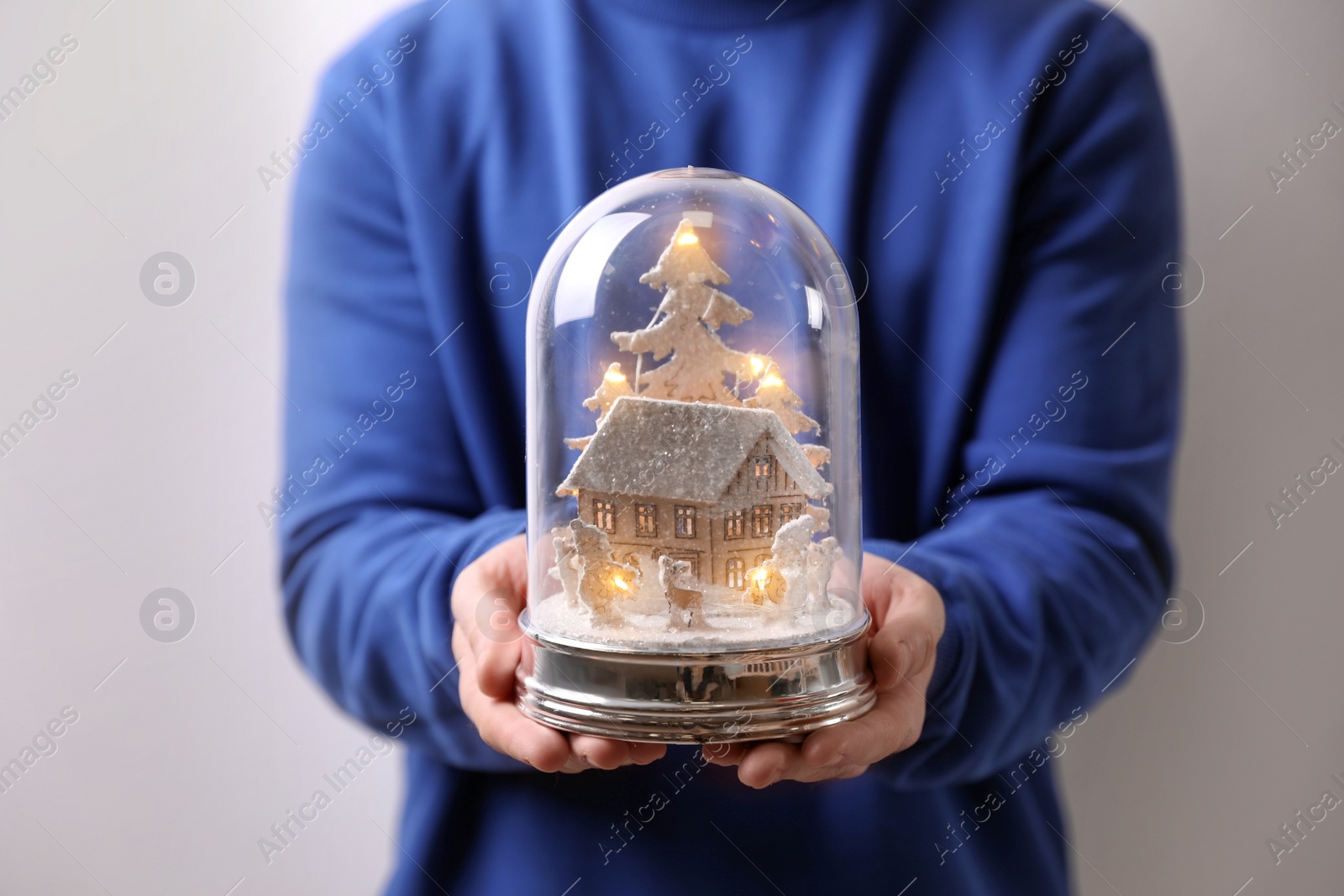 Photo of Man holding snow globe on light grey background, closeup